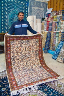 Pardavėjas Mohamedas kilimų parduotuvėje demonstruoja prekes